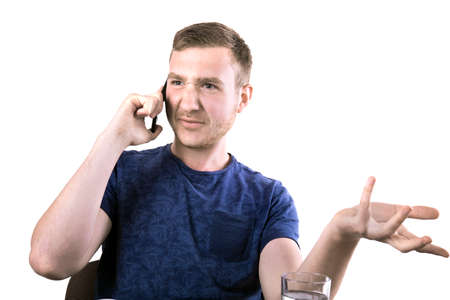 A disappointed and angry young man with a cell phone isolated over the white background. An annoyed...