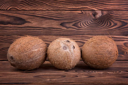 Three whole, exotic, tropical and bright brown coconuts, isolated on a white background. Close-up of...