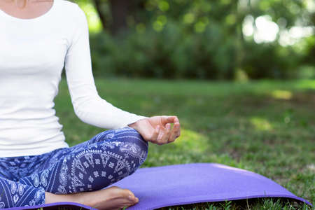 A close-up yoga lady sitting in a lotus position. A skinny sports girl sitting on a bright purple...