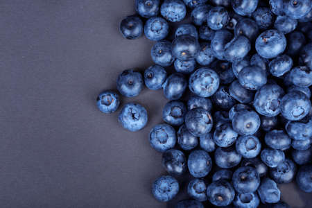 A view from above on a heap of nutritious blueberries on a bright black background. Tasteful and ripe blueberries. Refreshing and healthful blueberries for sweet summer smoothies and yogurts.の写真素材