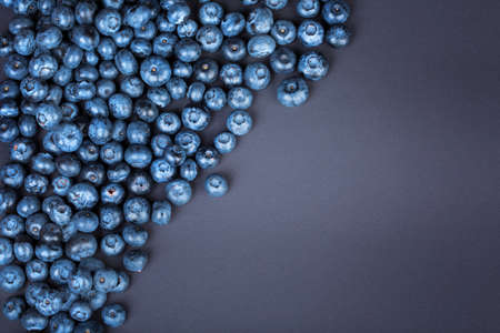 Top view of juicy and sweet blueberries on a dark purple background. Fresh, raw and ripe blueberries full of vitamins. Organic ingredients for nutritious summer desserts.の写真素材