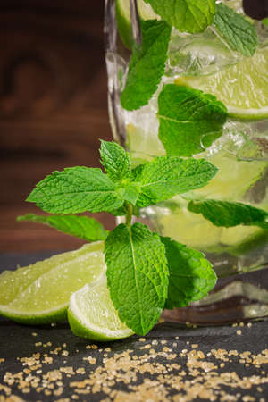 Close-up of a tasty organic beverage with fresh slices of lime, ice and leaves of mint, on a wooden background. Summer beverages.の写真素材