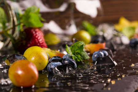 Sweet colourful berries with mint. Ripe yellow grapes, bright delicious bilberries, juicy strawberries and bright carambola with fresh mint. Summer harvest.の写真素材