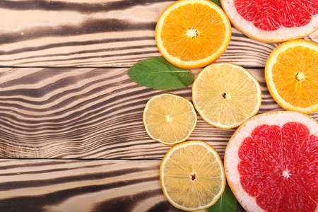 A view from above on different citruses on a brown wooden background. Red grapefruits on a spacious table. Sour yellow lemons and sweet oranges with a juicy texture. Tropical and summer fruits.の写真素材