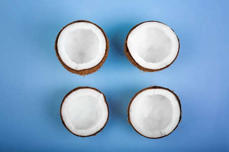 Four cut tropical and exotic coconuts on a light blue background. Nutritious exotic nuts. Tasty and bright brown nuts. Cut and sweet cocos. Fresh, ripe and organic fruit of coconuts.の写真素材