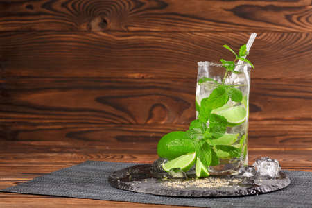 A glass of green mojito. Sour, cold and alcoholic mojito with lime and mint. Alcohol drink on a wooden background. Copy space.の写真素材