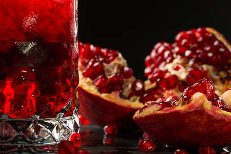 A close-up of a beautiful, ripe, juicy, colorful garnet and refreshing non-alcoholic berry drink on a black background. Health, organic, nature and antioxidant concept. Summer cocktails.の写真素材