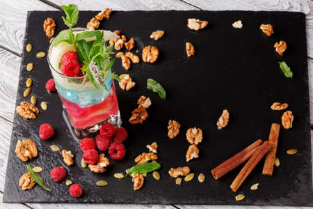 A top view on a beautiful composition of colorful organic milkshake with mint leaves, pink raspberries, cinnamon sticks and crunchy walnuts on a light table background. Healthy lifestyle. Copy space.の写真素材