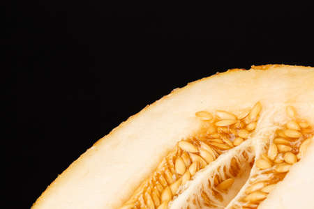 Close-up of a bright cut melon on a black background. A yellow melon full of vitamins. Melon honeydew with a juicy texture. Organic vegetarian ingredients for healthy and natural meals. Copy space.の写真素材
