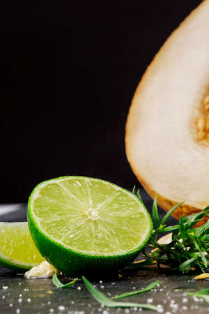 Close-up of bright fresh lime and sweet melon. Juicy exotic cut fruits on a black background. Summer...
