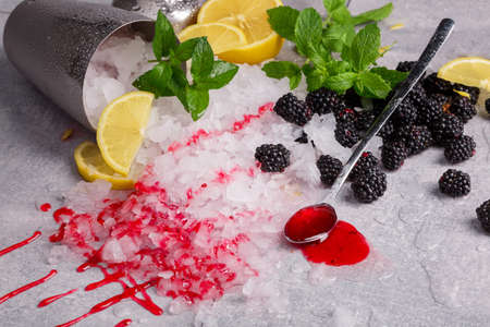 Close-up picture of a bucket with ice and a spoon with sweet jam on a gray background. Pile of mint...