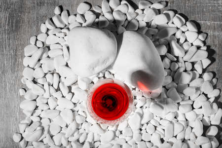 A top view of a glass of red wine on little white rocks on a gray background. Beautiful and luxurious grape beverage in a big glass. Cabernet, burgundy, bordeaux, merlot french wine.の写真素材