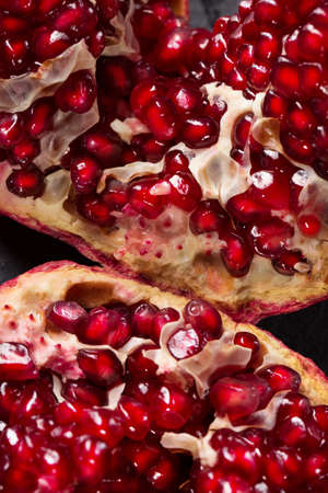 Useful red garnet berries for desserts or drinks used as a background. Macro photo of ripe bright red pomegranate cut into pieces. Beneficially and nutritious vitamins closeup.の写真素材
