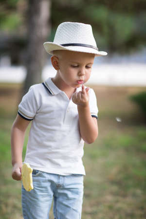 Adorable boy looking at his finger. Kid with a lollipop on a natural background. A child having fun outdoors in summer.の写真素材