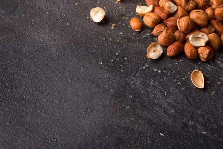 A view from above on salty appetizer for beer on a saturated black stone background. Small heap of nutritious roasted crispy hazelnuts. Peeled brown nuts. Copy space.の写真素材