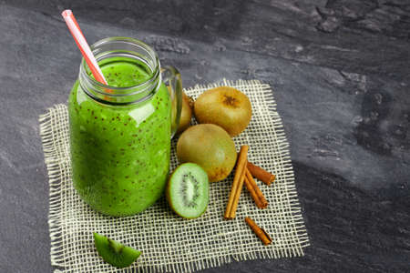 Top view of juicy smoothie for detoxication. Composition of healthy ingredients on a gray background. Glass of kiwi juice.の写真素材