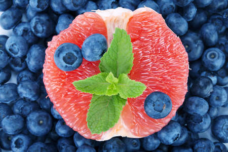 A bitter grapefruit, sweet blueberries and fresh mint as a background. Nutritious citrus in a center of bilberries.の写真素材