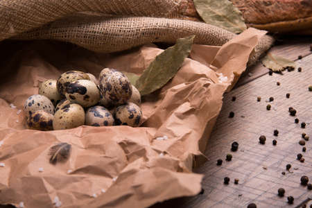 Closeup of nutritious quail eggs, dried up bay leaves and different seasonings on a light wooden background.の写真素材