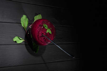 A healthy vegetable wine-colored snack with spoon and green leaves on a table background. Grated...
