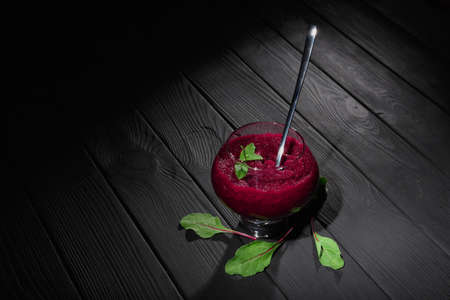 Top view of grated beet in a dessert glass on a table background. A vegetable wine-colored snack with spoon and green leaves.の写真素材