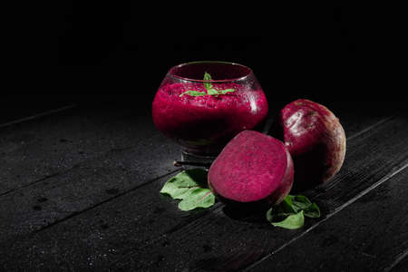 Close-up of a transparent glass with claret-coloured snack on a black background. Healthy food with beet, mint and sugar.の写真素材