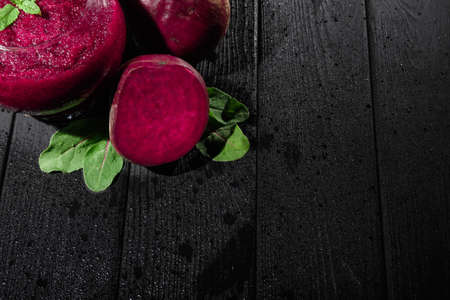 Red beets and leaves on a black background. Beetroot and mint juice in a glass. Luxurious vegan cocktails. Copy space.の写真素材