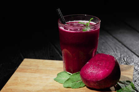 Organic juices. Fresh summer vegetable cocktails. Cut and blended beets on a black background. Red smoothie with mint.の写真素材