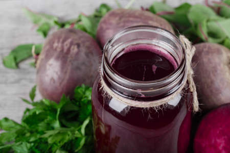 Healthful red cocktail on a gray background. A glass jar of beetroot juice and green salad. Veggie drinks for gourmets.の写真素材