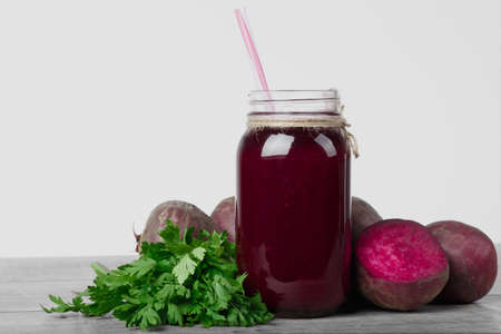 Beetroot juice. A bottle of vegetable cocktail isolated on a white background. Beets and greens on a table. Copy space.の写真素材