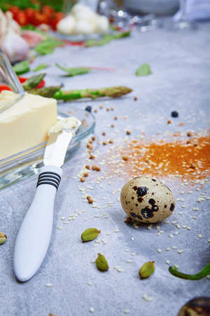 Macro picture of a glass container with butter next to a metal butter knife on a gray background....