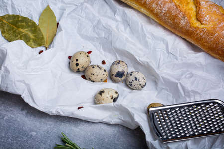 Macro picture of lunch ingredients on a grese-proof paper background. French baguette, metal grater,...
