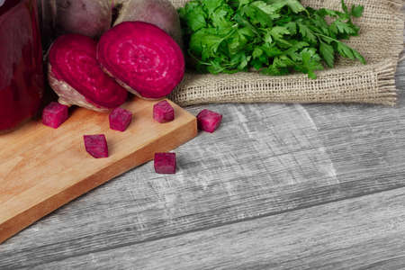 Close-up of a healthful composition of whole and sliced beetroots and parsley on a light fabric and...