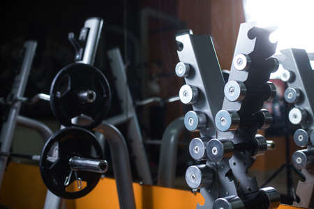 A stand with barbells in a gym. Dumbbells holder on a blurred background. Sports equipment. Fitness,...
