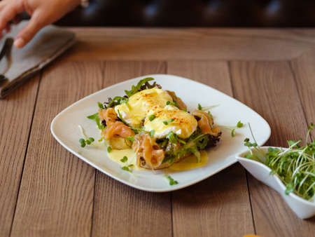 Waitress serving a lunch close-up. Poached eggs on a table backgの写真素材