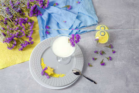 Organic sweet milkshake. A glass of cocktail with fruits on a table background. Decorative flowers, lemon and fabric.の写真素材