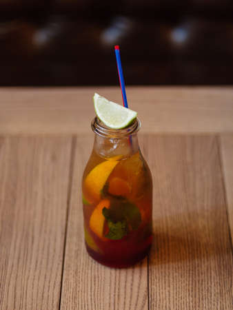 A wooden table with a fresh cocktail, cool juice, slices of oranges and green sappy leaves of mint on a blurred dark wooden background. Cold alcohol drinks.の写真素材