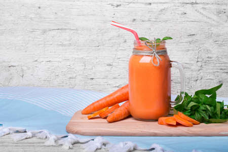 Close-up of a nutritious vitamin cocktail. Big mason jar filled with thick carrot beverage on a gray table background.の写真素材