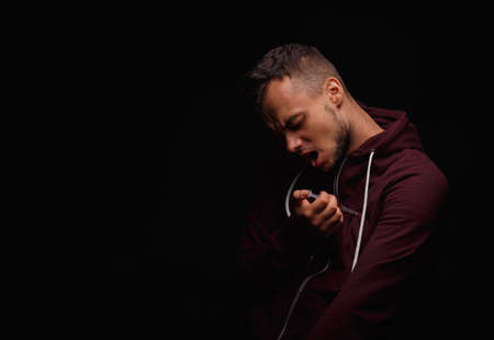 A guy killing himself with a drug syringe. Addicted, sick man taking drugs on a black background. Drugs kill concept.の写真素材