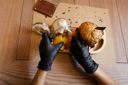 A view from above on a fast food composition on a wooden table background. Fat meat burger and rustic potatoes on a wooden tray. Junk food. American burger. Cooking, fast food, concept.の写真素材