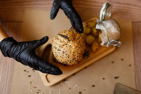 A view from above on a fast food composition on a wooden table background. Fat meat burger and rustic potatoes on a wooden tray. Junk food. American burger. Cooking, fast food, concept.の写真素材