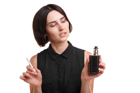 A young female deciding between a vaping device and a cigarette isolated on a white background....