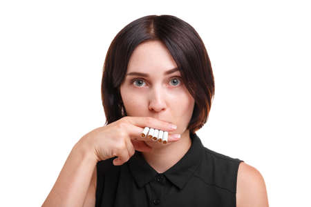 Close-up of a girl smoking cigarettes. A  smoking addict isolated on a white background. Unhealthy lifestyle concept.の写真素材
