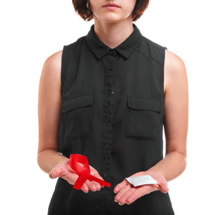 A girl holding a condom and a red ribbon isolated on a white background. Medical support. Safe sex...