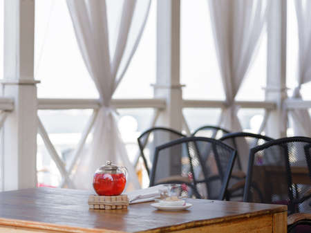 A teapot full of hot beverage from juicy strawberries and red currant on a cafe window background....