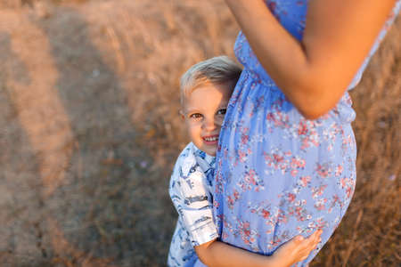 Close-up of a happy little son hugging a tender mom on a blurred natural background. Childhood, family concept.の写真素材
