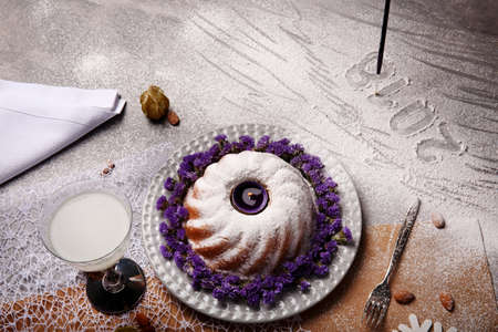 A top view of a Christmas pudding sprinkled with sugar powder and decorated with flowers on a light...