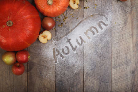 A view from above on an orange composition on a wooden table background. Bright autumn pumkins and apples next to a sugar inscription. Autumn harvest. Rustic concept. Copy space.の写真素材