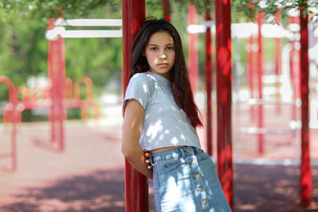 A close-up of a young girl in casual clothes on a blurred athletic field background. Fashion, urban, youth concept. Copy space.の写真素材
