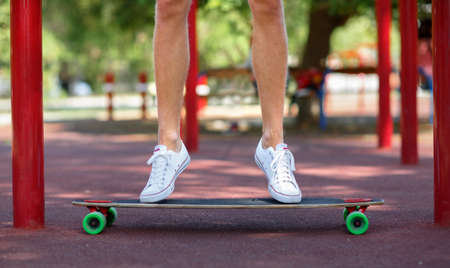 Close-up picture of teenagers' legs in white gumshoes on the sports ground background. A sportive...
