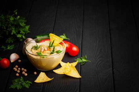 A still life of a glass bowl full of nutritious paprika hummus made of chickpea. Arabic dish...